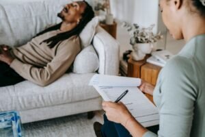 Crop anonymous African American female with paper form talking to male partner during psychotherapy in living room